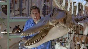 Een foto van presentator Freek die in een museum naast een skelet staat van een Orka. De Orka is een roofdier en familie van de Dolfijn.