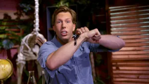 Een foto van presentator Freek met op zijn arm een schorpioen. Achter hem staat een skelet van een giraf.