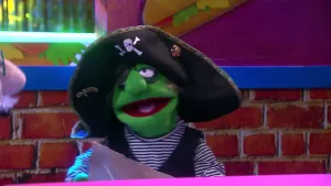 Een foto van een pop die verkleed is als piraat. Hij heeft een gestreept shirt aan, een ooglapje over een oog en een piratenhoed op. In zijn handen houdt hij een vel papier.