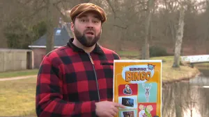 Een foto van presentator boswachter Tim die buiten een bingo kaart vasthoudt en met zijn vinger erop wijst.