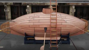 Een foto van een houten onderzeeboot gebouwd door uitvinder Cornelis Drebbel. Er staat een ladder tegenaan waarmee je aan de bovenkant de duikboot mee in kan klimmen.