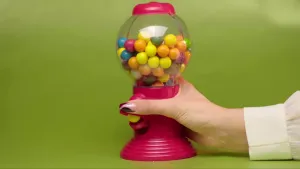 Een foto van de hand van iemand die een snoep automaat vasthoudt.