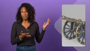 Een foto van een presentator voor een paarse achtergrond. Rechts staat een foto in beeld van een oud kanon met een goud en zilverkleurige loop, het deel waar de kogel uitkomt. Van de wielen zijn de spaken blauwgrijs en de randen erom goudkleurig.