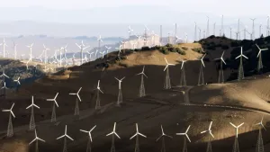 Een foto van een landschap met zanderige heuvels. Het staat vol met windmolens. Je ziet er wel honderd. 