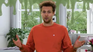 Een foto van presentator Tim die zijn handen met de handpalmen omhoog houdt, om aan te geven dat hij iets niet weet. Boven Tim zijn naar beneden hangende druppels groene slijm getekend, die neusslijm van een mens voorstellen. 