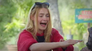 Een foto van presentator Emma die vol met angst naar een wespspin kijkt die over haar hand loopt.