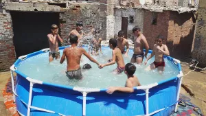 Een foto van een rond zwembadje in Egypte. Het staat tussen de huizen. Erin zijn tien jongens aan het spelen. 