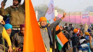Een foto van Indiase boeren die in India aan het protesteren zijn. Er zijn Indiase vlaggen te zien en verschillende spandoeken met Indiase teksten erop.