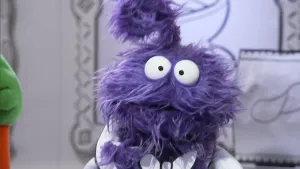 Een foto van een paarse pop die recht in de camera kijkt in het museum van gewone dingen.