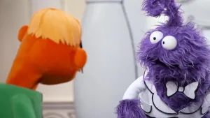 Een foto van een oranje pop die met een paarse pop aan het praten is in het museum van gewone dingen.