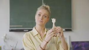 Een foto van presentator Janouk die in de camera terwijl ze een plastic giraf voor haar houdt in haar handen.