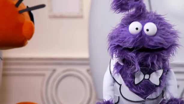 Een foto van een paarse pop die tegenover een oranje pop staat in het museum van gewone dingen.