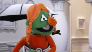 Een foto van een groene pop die aan het praten is in het museum van gewone dingen.