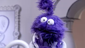 Een foto van een paarse pop die voor de camera staat in het museum van gewone dingen.