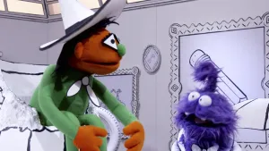 Een foto van een oranje pop die in een gebroken pot zit en een paarse pop die tegen de oranje pop praat.