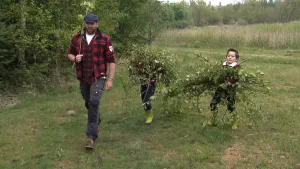 Een foto van boswachter Tim met twee kinderen die wandelen met takken in de handen.