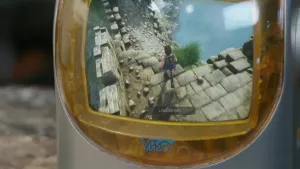 Een foto van een oude televisie. Op het beeld ervan zie je een computer game. De televisie heeft een gele plastic rand met daarop in blauwe letters "VPRO".