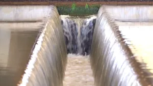 Een foto van water dat links en rechts in beeld is, en naar het midden stroomt. Daar stroomt het naar beneden, net als in een waterval. 