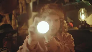 Een foto van Pascal met een zaklamp in zijn handen. De zaklamp brand met een helder licht richting de camera en daardoor is alleen de ronde cirkel van licht zichtbaar en niet het deel van de lamp dat Pascal vastheeft. Pascal draagt een lichtbruine muts. 