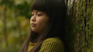 Een foto van een jong meisje. Ze heet Kyona en leunt tegen de knuffelboom. Ze kijkt bezorgd.