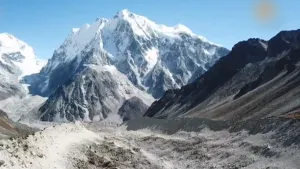 Een foto van een berggebied. Op de voorgrond zie je een gletsjer en op de achtergrond een hoge berg met sneeuw erop.
