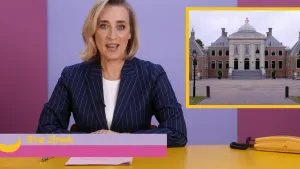 Een foto van Eva Jinek die achter een bureau zit. Voor haar liggen papieren en een pen. Naast haar staat een telefoon. Rechts in beeld zie je een foto van de woning van koning Willem-Alexander.