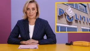 Een foto van Eva Jinek. Ze zit achter een bureau en kijkt in de camera. Voor haar liggen wat papieren en een pen. Naast haar staat een telefoon. Rechts in beeld zie je een foto van een politiebureau.