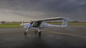 Een foto van een klein vliegtuigje op een startbaan. Het vliegtuigje heeft vooraan een propeller. Er zit een man in het vliegtuigje.