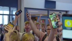 Een foto van scholieren die hun telefoons boven hun hoofd houden.