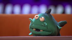 Een foto van een pop die Victorina Vergiet heet en vaak dingen vergeet. Het is een vis en ze heeft groene tot donkergroene huid en vinnen, grote ronde ogen en twee witte tanden in haar iets geopende bek. Ook heeft ze twee snorharen boven haar lip. 