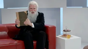 Een foto van een oudere man die het boek "The Descent of Man" geschreven door Charles Darwin laat zien. In het Nederlands is de naam van het boek "De afstamming van de mens".