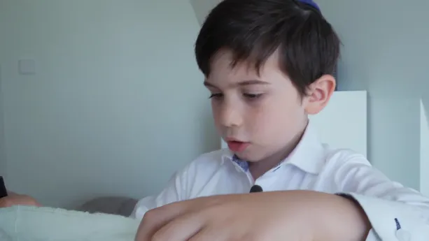 Een foto van een Joods jongetje die met kleding bezig is.