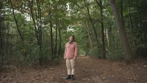 Een foto van presentator Pascal die op een weg staat middenin het bos.
