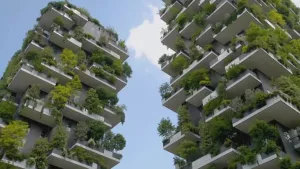 Een foto van twee flatgebouwen. Je kijkt er vanonder tegenaan. Je ziet op alle balkons bomen en struiken. 