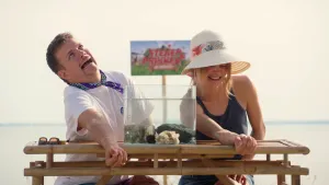 Een foto van Jurre en Emma die buiten aan een tafel zitten. Op de tafel staat een glazen bak met water en een Zee-egel erin. Jurre en Emma hebben allebei een arm op de tafel en ze hebben allebei pijn.