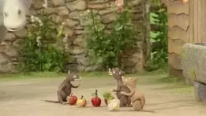 Een foto van drie ratten die buiten op de grond zitten. Ze hebben stenen geverfd zodat die op appels en knollen lijken. Op de achtergrond zie je een stenen muur.