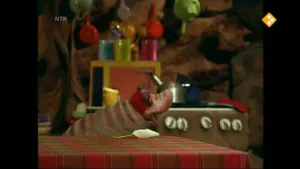 Een foto van Piertje thuis. Ze zit aan tafel. Op die tafel ligt een muis. Op de achtergrond zie je een fornuis en er hangen pannen aan de muur. 