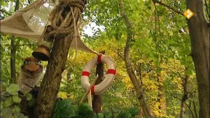 Een foto van Arie in het bos. Naast Arie zie je een lamp, wat touwen, een doek en een reddingsboei aan de boom hangen. 