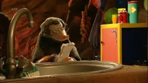 Een foto van Moffel. Hij is binnen en kijkt naar een opschrijfboekje. Op de voorgrond zie je een kraan met een wasbak. 