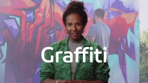 Een foto van een presentator met op de voorgrond de woorden "Graffiti". Op de achtergond is een foto te zien van een man die graffiti aan het spuiten is op een betonnen muur. De graffiti vormt een niet-leesbare tekst in rode en paarse kleuren op de muur.