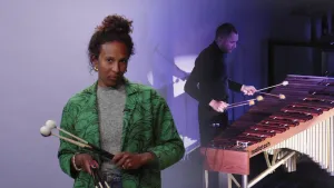 Een foto van een man die een Marimba bespeelt met stokken en daarnaast een foto van een presentator die ook stokken vastheeft.    De marimba is een Afrikaans slaginstrument met toetsen van houten blokjes die je met twee tot zes stokken kunt bespelen. 