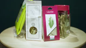 Een foto van een rond tafeltje. Daarop staan drie zakjes met laurierblaadjes erin en een potje met laurierblaadjes. Ze zijn van verschillende merken.