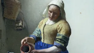 Een foto van de bovenkant van het schilderij "Het melkmeisje" van de Nederlandse schilder Johannes Vermeer. Op het schilderij schenkt het melkmeisje melk uit een melkkan, die nog net te zien is en kijkt naar beneden. Ze draagt kleding uit de 17e eeuw.