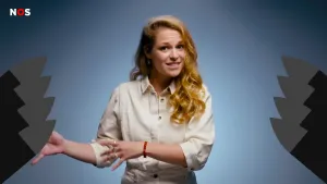 Een foto van een presentator die in de camera kijkt en met gespreide vingers van beide handen naar links wijst. Aan beide zijkanten van de foto zijn vier omhoogwijzende punten van nucleaire raketten getekend. De raketten zijn zwart met een grijse kop.