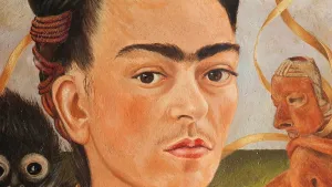 Een schilderij van het gezicht van schilder Frida Kahlo, door haarzelf. Ze heeft duidelijk doorlopende wenkbrauwen en een licht snorretje. Achter haar zijn een aapje en een mexicaans beeld.
