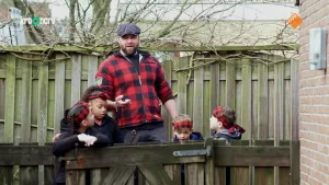 Een foto van boswachter Tim die samen met vier kinderen achter een hek staan in een achtertuin. Achter hun is een schutting te zien.