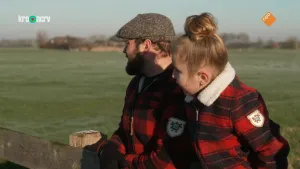 Een foto van boswachter Tim die samen met een meisje tegen een hek aanleunt tussen de weilanden.