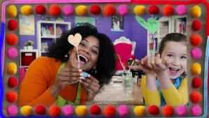 Een foto van Stephanie en Ilva die allebei een geknutselde pennenhouder vasthebben. De pennenhouder bestaat uit een papieren hartje op een staande ijzerdraad waar allemaal kralen aanzitten. Het kan stevig blijven staan door het steentje dat eronder zit.