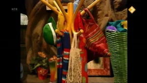 Een foto van een kapstok. Aan die kapstok hangen tassen, sjaals en een groene hoed. 