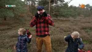 Een foto van boswachter Tim die samen met twee meisjes op de hei staat. Boswachter Tim houdt zijn handen bij zijn gezicht.